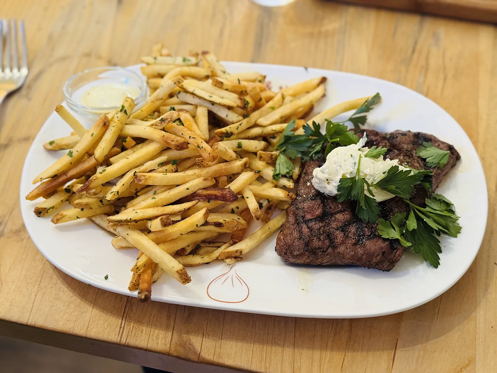 Steak frites with herb butter on a white plate