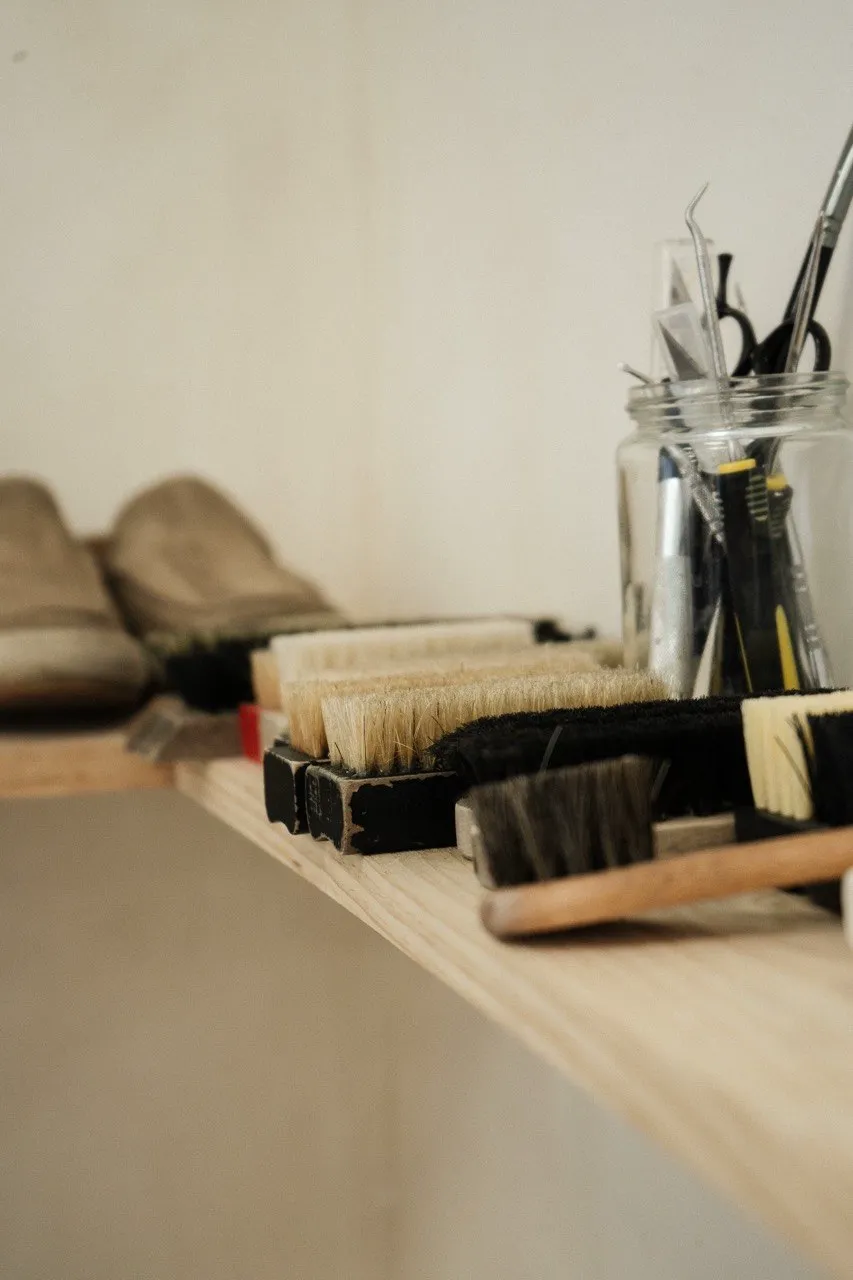 Neck brushes and tools lined up on a wooden shelf in the shop