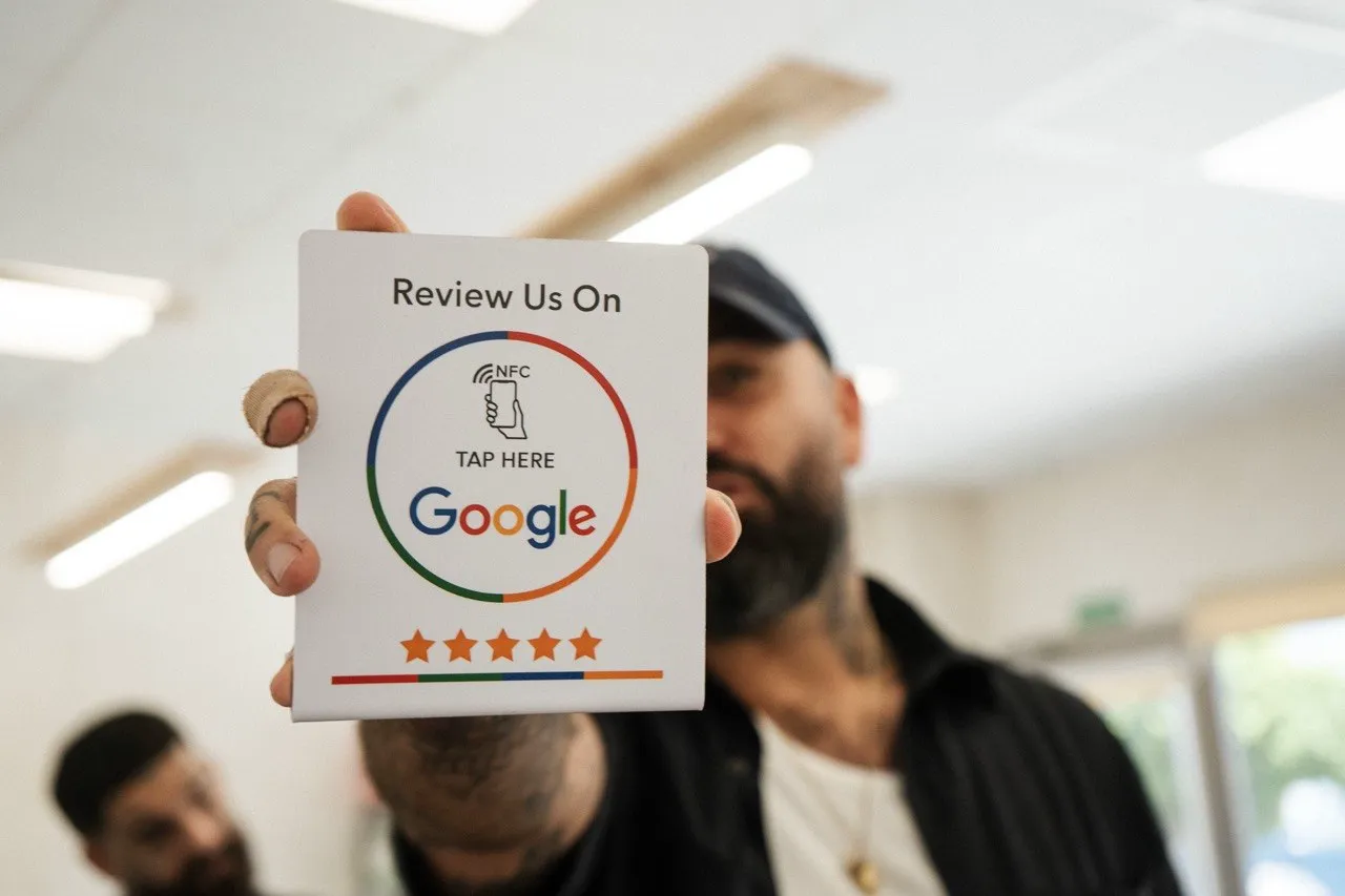 A Harrisons barber holding up the tap-to-review Google card in the shop