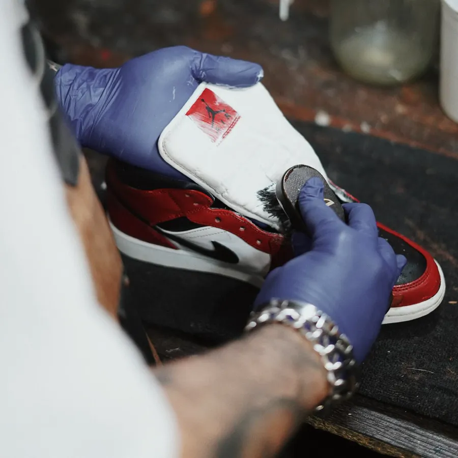 Gloved hands brush-cleaning a pair of Jordan 1s at the Sole Brothers station